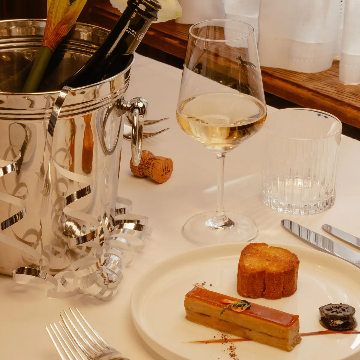 Gedeckter Tisch mit Sektkühler, Weinglas und Dessert